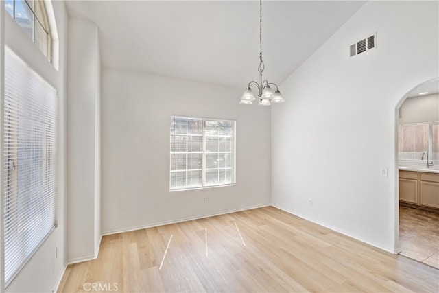 empty room featuring light hardwood / wood-style flooring, a chandelier, sink, and high vaulted ceiling