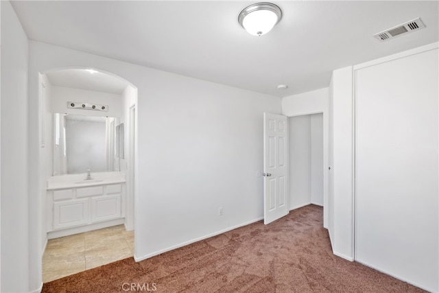 unfurnished bedroom featuring connected bathroom, carpet flooring, and sink