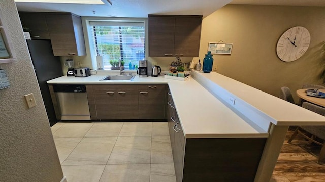 kitchen with kitchen peninsula, dishwasher, a kitchen bar, dark brown cabinetry, and sink