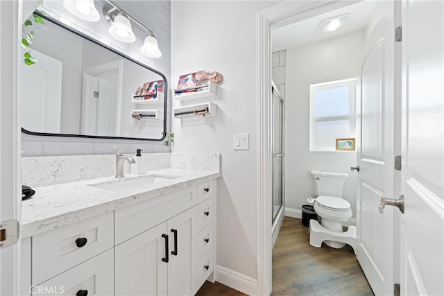 bathroom with wood-type flooring, vanity, toilet, and an enclosed shower