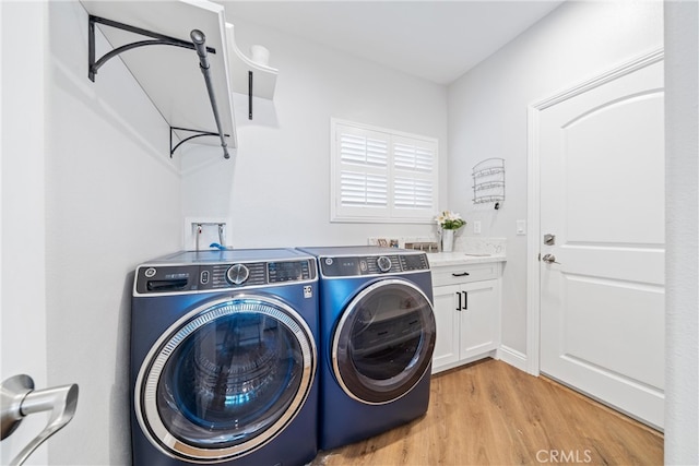 washroom with light hardwood / wood-style flooring, cabinets, and washer and clothes dryer