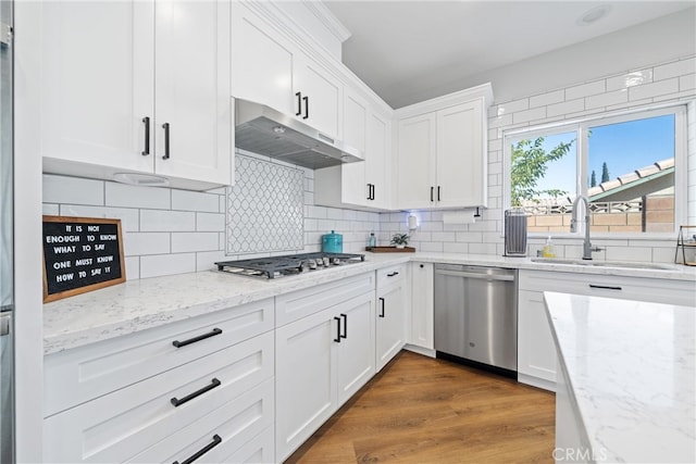 kitchen with white cabinets, sink, tasteful backsplash, appliances with stainless steel finishes, and hardwood / wood-style floors