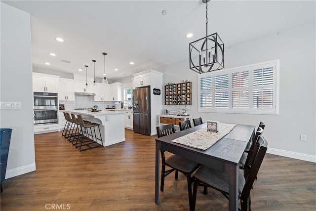 dining area with an inviting chandelier, sink, and dark wood-type flooring