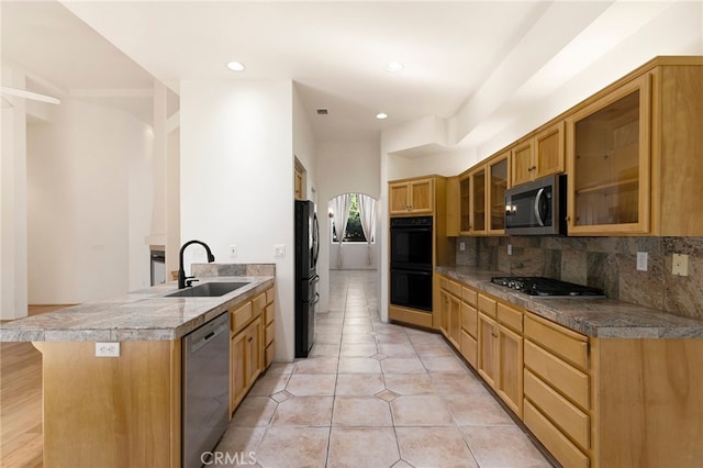 kitchen with sink, a breakfast bar area, black appliances, light tile patterned flooring, and decorative backsplash