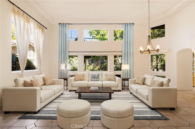 living room with a towering ceiling, plenty of natural light, and a notable chandelier