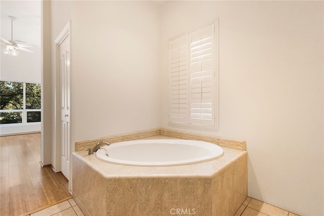 bathroom with a relaxing tiled tub, tile patterned flooring, and ceiling fan