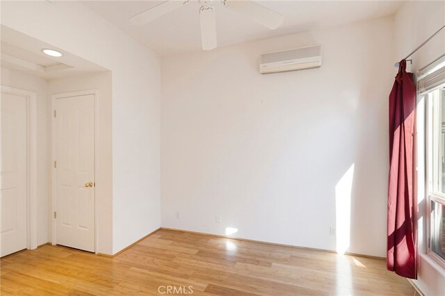 spare room featuring ceiling fan, light hardwood / wood-style floors, and a wall mounted AC