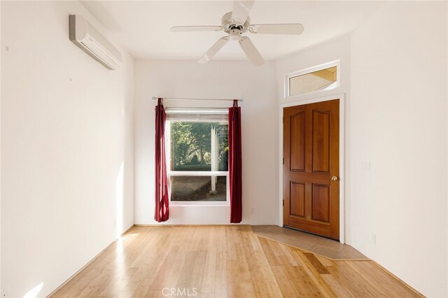 foyer entrance featuring light hardwood / wood-style flooring, an AC wall unit, and ceiling fan