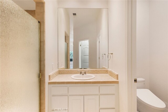 bathroom featuring vanity, a shower with shower door, and toilet