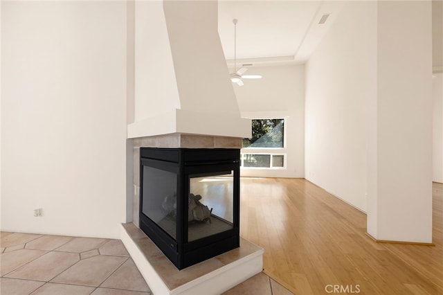 interior details featuring ceiling fan, a multi sided fireplace, and wood-type flooring