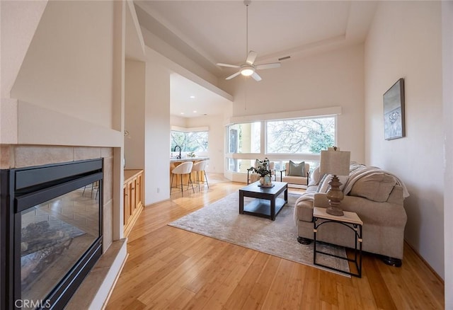 3185 Via Casita Pl, Chico, CA 95928 - living area featuring light wood finished floors, a ceiling fan, a tile fireplace, a tray ceiling, and a towering ceiling