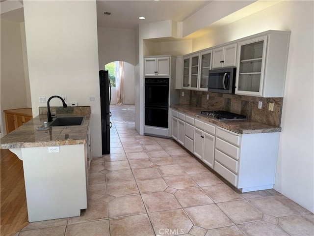 3185 Via Casita Pl, Chico, CA 95928 - kitchen with stainless steel appliances, arched walkways, glass insert cabinets, decorative backsplash, and white cabinetry