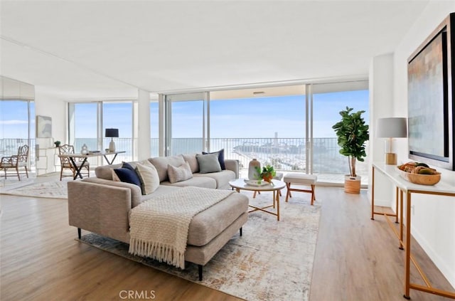 living room with floor to ceiling windows, a water view, and wood-type flooring