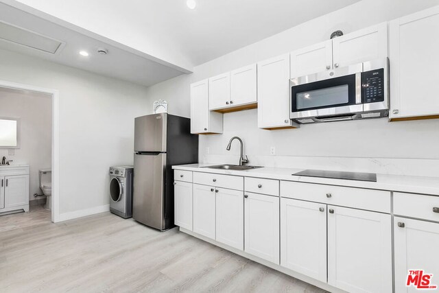 kitchen featuring stainless steel appliances, washer / dryer, light hardwood / wood-style floors, and white cabinets