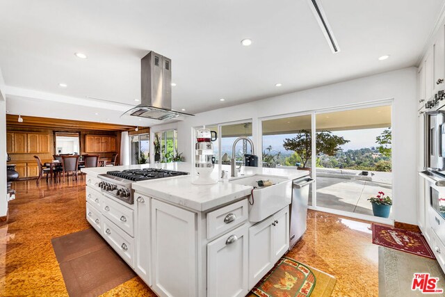 kitchen with sink, white cabinetry, island exhaust hood, appliances with stainless steel finishes, and light stone countertops