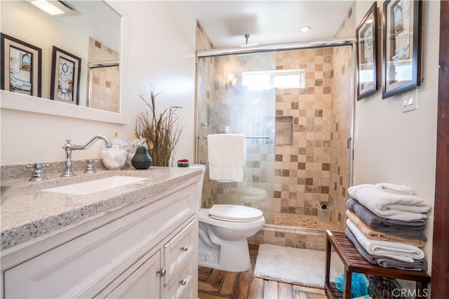 bathroom with walk in shower, vanity, toilet, and hardwood / wood-style flooring