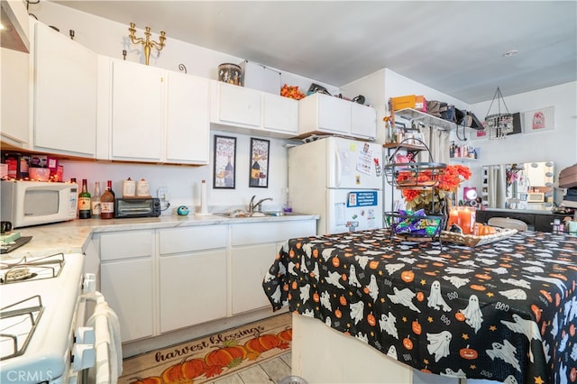 kitchen featuring sink, white appliances, and white cabinetry