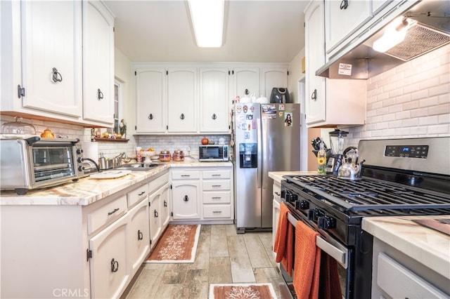 kitchen with appliances with stainless steel finishes, decorative backsplash, light hardwood / wood-style floors, white cabinets, and sink