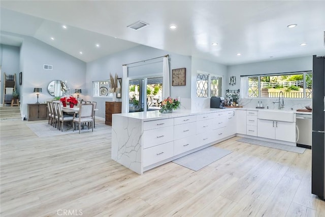 kitchen featuring sink, stainless steel dishwasher, kitchen peninsula, light hardwood / wood-style floors, and white cabinets