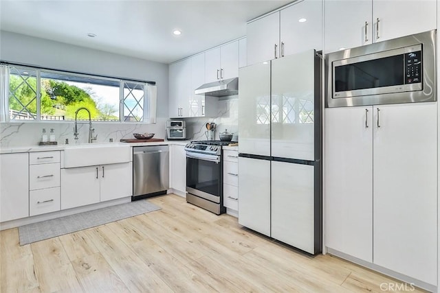 kitchen with white cabinetry, appliances with stainless steel finishes, sink, and backsplash