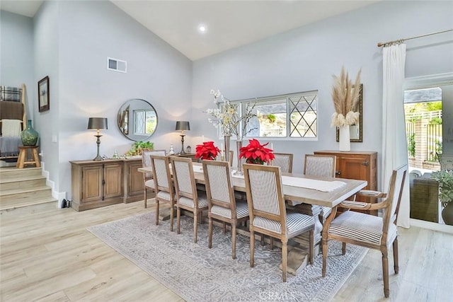 dining area with high vaulted ceiling and light wood-type flooring