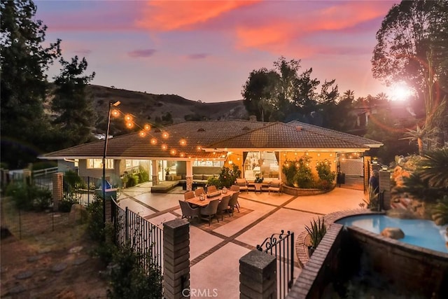 back of property featuring a tile roof, a patio, fence, outdoor lounge area, and a hot tub