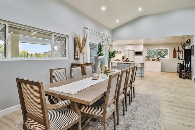 dining area with high vaulted ceiling and light wood-type flooring