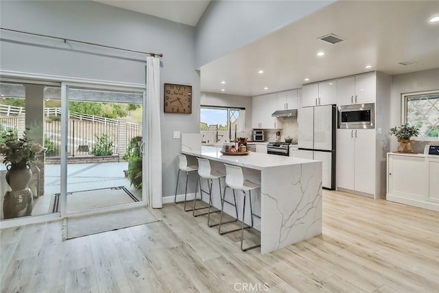 kitchen featuring stainless steel appliances, white cabinets, light hardwood / wood-style floors, and kitchen peninsula