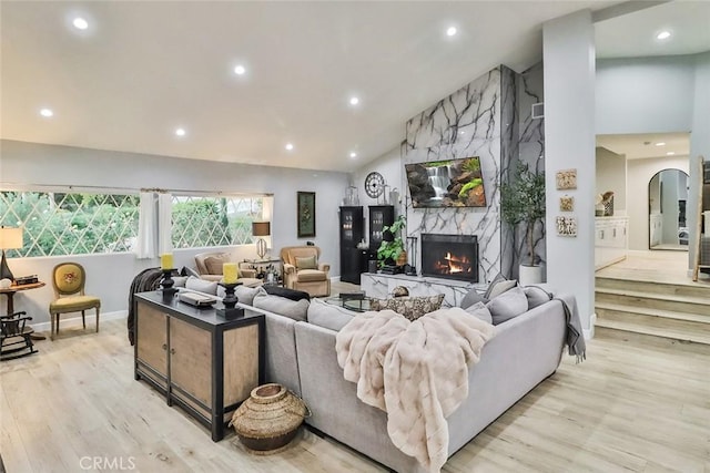 living room featuring lofted ceiling, a high end fireplace, and light hardwood / wood-style flooring