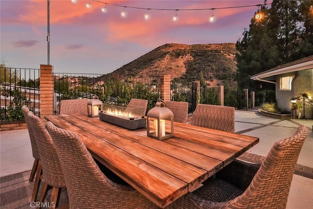 patio terrace at dusk featuring a mountain view and an outdoor fire pit