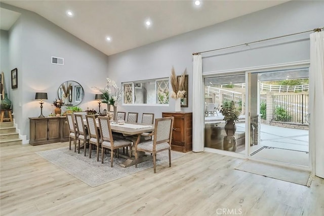 dining area featuring high vaulted ceiling and light wood-type flooring