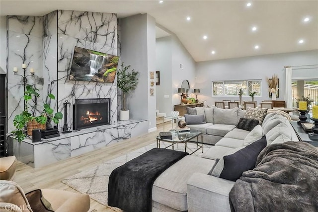 living room featuring light hardwood / wood-style flooring, a high end fireplace, and high vaulted ceiling