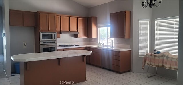 kitchen with a notable chandelier, stainless steel appliances, tile counters, a breakfast bar, and light tile patterned floors