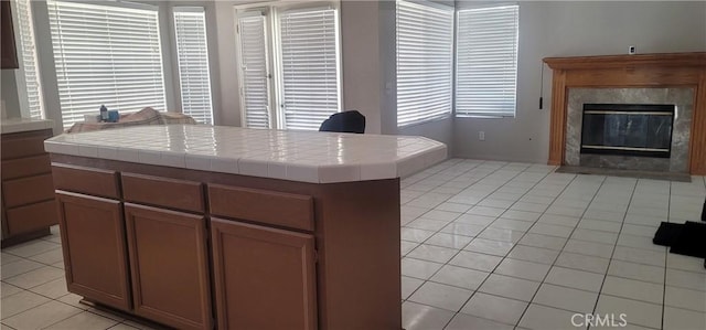 kitchen featuring light tile patterned floors, a premium fireplace, tile countertops, and a kitchen island