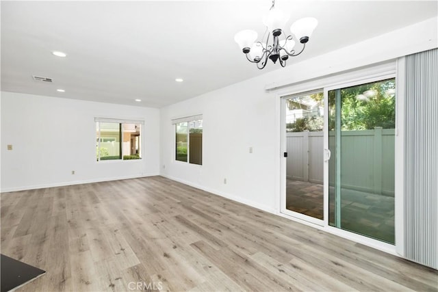 spare room with a notable chandelier and light hardwood / wood-style flooring