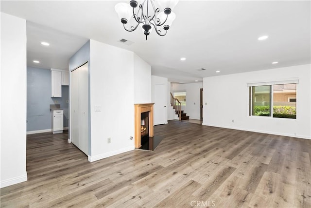 unfurnished living room featuring a chandelier and light wood-type flooring