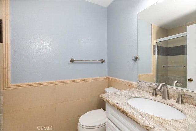 bathroom with walk in shower, vanity, toilet, and tile walls