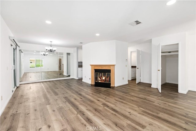 unfurnished living room with a chandelier and hardwood / wood-style floors