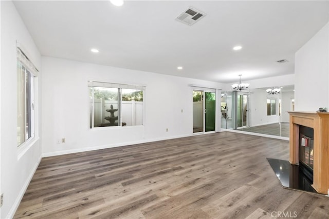 unfurnished living room featuring wood-type flooring and a notable chandelier