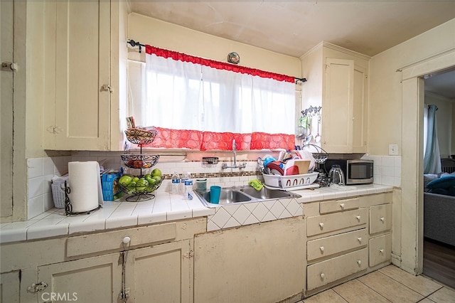 kitchen with tile countertops, tasteful backsplash, sink, and light tile patterned floors