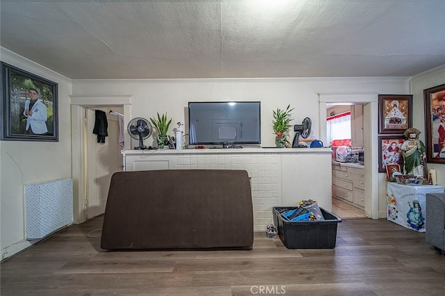 living room featuring ornamental molding, wood-type flooring, and a textured ceiling