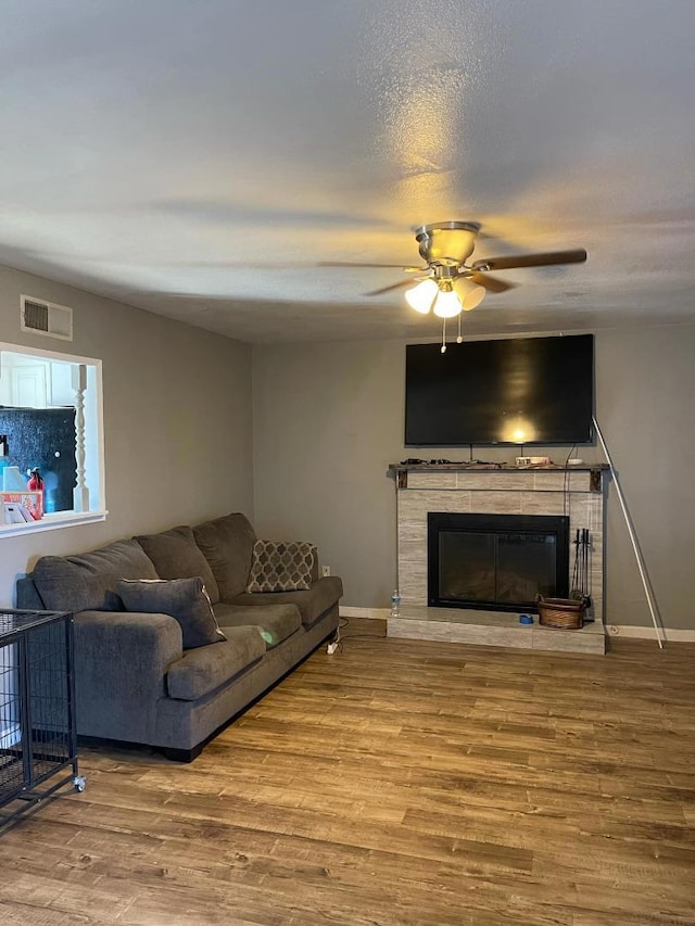 living room featuring ceiling fan, wood-type flooring, and a fireplace