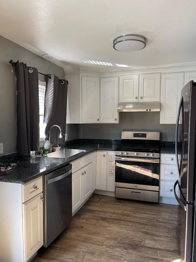 kitchen featuring dark wood-type flooring, dark stone counters, sink, appliances with stainless steel finishes, and white cabinetry