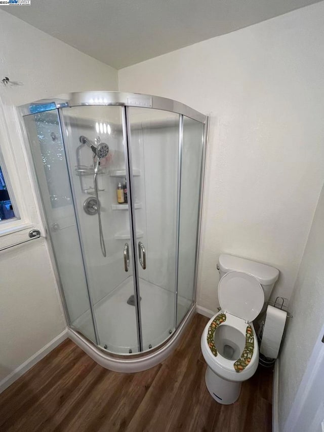 bathroom with a shower with door, toilet, and hardwood / wood-style flooring