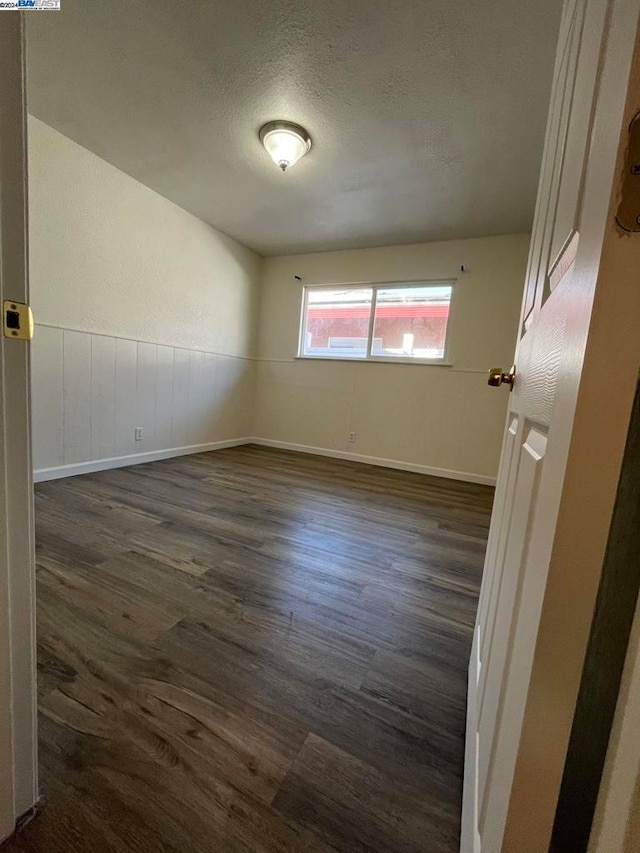 unfurnished room with a textured ceiling and dark hardwood / wood-style flooring