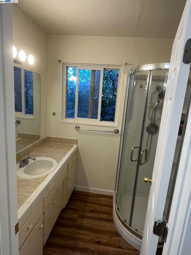 bathroom with wood-type flooring, vanity, and an enclosed shower