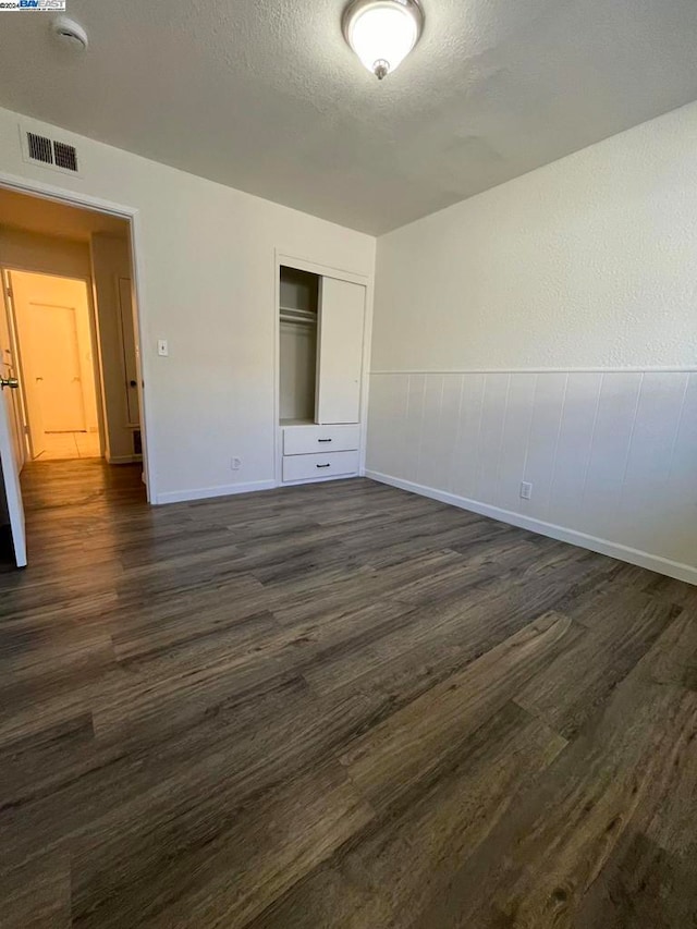 unfurnished bedroom featuring a textured ceiling, a closet, and dark hardwood / wood-style floors