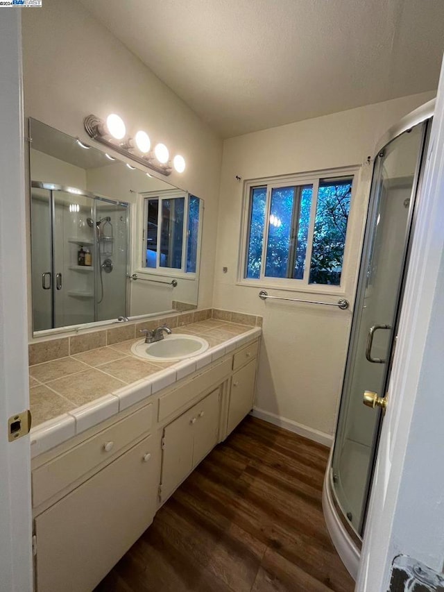 bathroom featuring hardwood / wood-style floors, a shower with shower door, and vanity