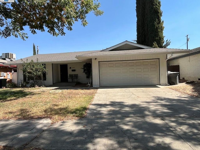 single story home with cooling unit and a garage