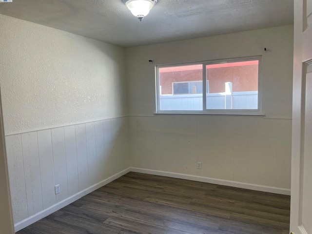 unfurnished room featuring a textured ceiling and dark hardwood / wood-style floors